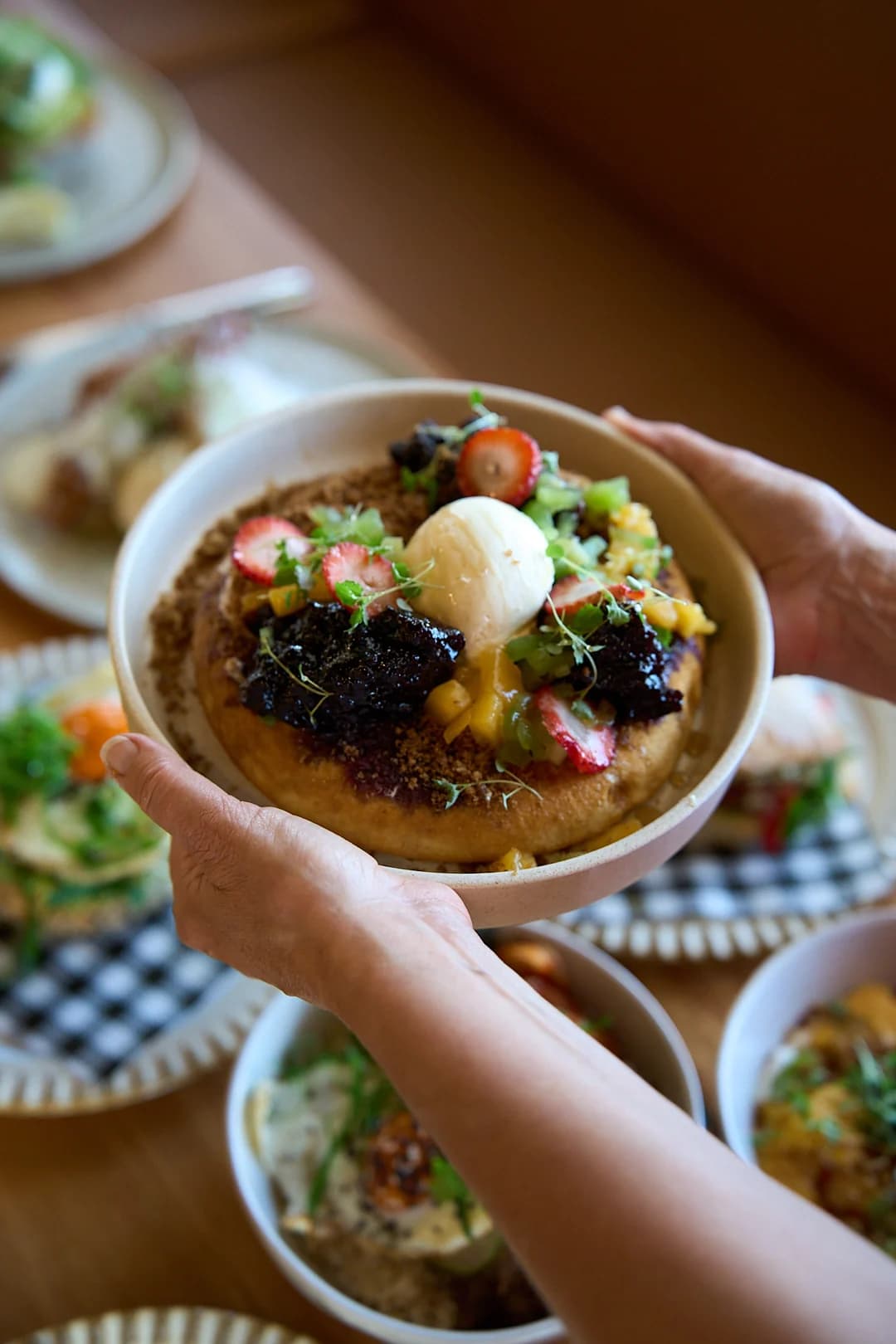 Hands presenting a colourful café dish