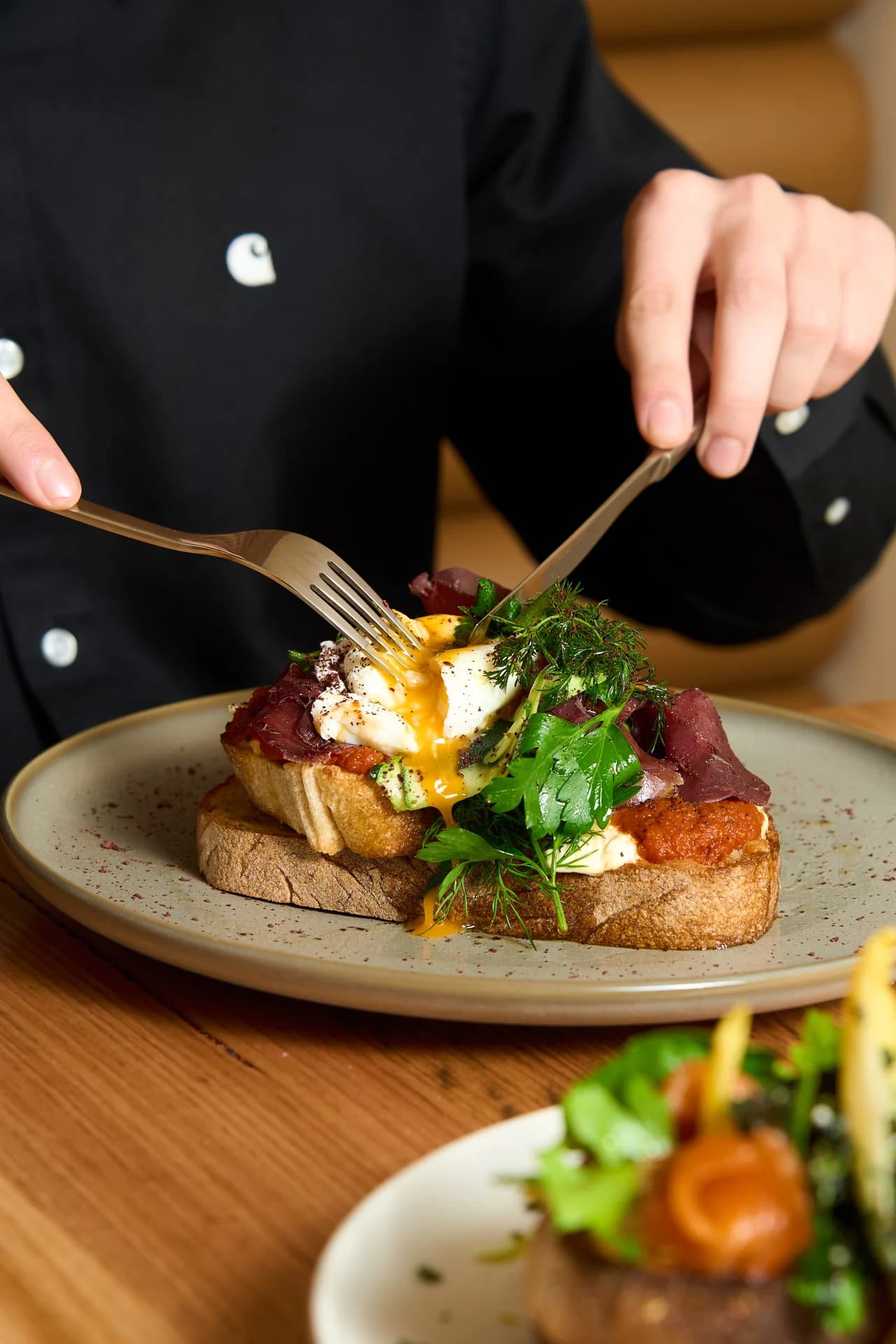A diner cutting into a plated breakfast at a café